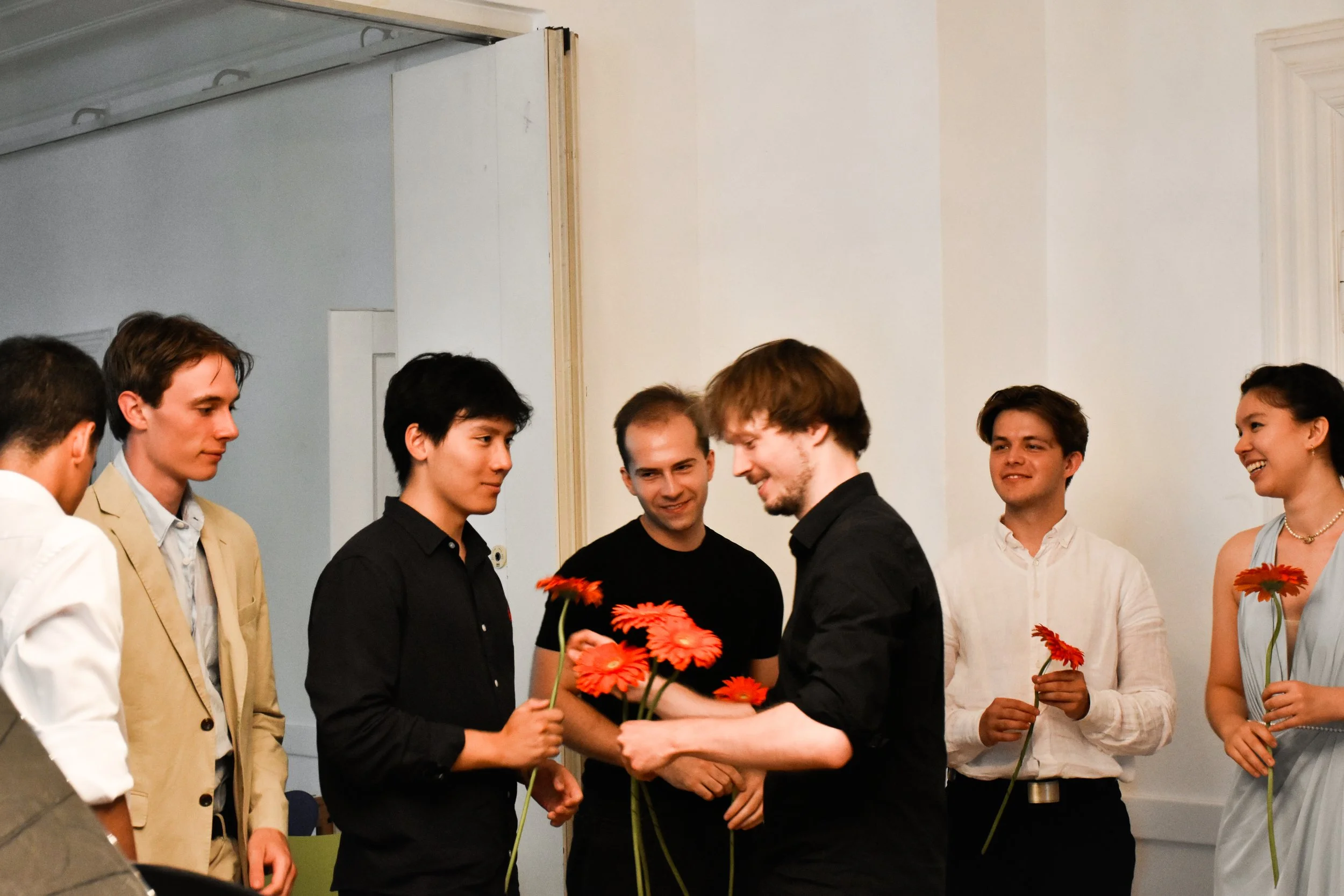 Eine Gruppe junger Menschen, die sich bei einer Feier mit Blumenstielen in den Händen versammeln.